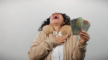 Orta yaşlı bir kadın, elinde Romanya banknotları tutarak gülerken beyaz bir arkaplanda, mali başarı ve neşe somutlaştırıyor..