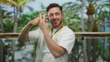 Steteskoplu genç doktor, sağlık ve modern iletişim kavramlarını vurgulayan yemyeşil arka planlı park ortamında hashtag yapıyor..