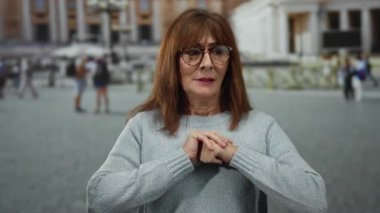 Tarihi mimarisi olan bir şehir meydanında gülümseyen kadın, Vatikan 'da bir kalabalıkla çevrili..