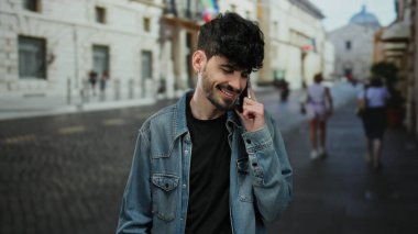 Kot ceketli, sakallı genç adam şehir sokağında telefonda konuşuyor, geçmişi bulanık..