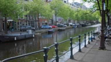 Suya yansıyan ağaçlar, binalar ve teknelerin bulanık manzarası bulanık. Odaklanamayan, bokeh etkisine sahip sakin ve huzurlu bir atmosfer yaratıyor..