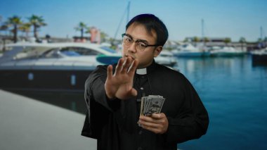 Dini giysiler giyen bir adam açık havada Çin 'de yatları olan deniz kıyısındaki limanda dolarları elinde tutuyor. Bu da bize açık denizde inanç ve para temalarını öneriyor..