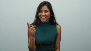 Tepedeki Latin kadın beyaz arka plan karşısında neşeli bir ifadeyle parmaklarını sayıyor, izole bir ortam, neşeli ve gündelik tavırları vurguluyor..