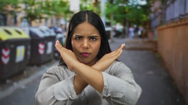 Şehir caddesinde çapraz silahlarla onaylamadığını belirten kadın, şehir manzarasının ortasında dikkat çekmek için bağırarak kararlı duruşunu vurguluyor..