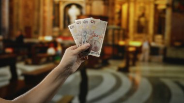 Güzel dekore edilmiş bir kilisenin içinde elinde Türk lirası tutan adam, modern para birimi ile tarihi mimari arasındaki zıtlığı yakalıyor..
