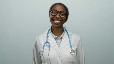 Steteskopla gülümseyen beyaz önlüklü bir kadın izole bir arka planda tıbbi profesyonelliği ve sağlık ortamında sıcaklığı somutlaştırıyor..