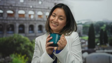 Roma kolezyumunun önünde kahve fincanı tutan gülümseyen kadın, kültürü harmanlıyor ve simgesel bir italyan ortamında seyahat ediyor..