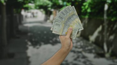 Endonezya Rupiah 'ı elinde tutan adam şehir sokaklarında döviz kurunu ve finansal kavramları ön plana çıkarıyor..