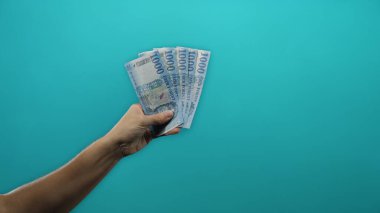 İzole edilmiş mavi arka plan duvarına karşı elinde Macar forint banknotları tutan adam..