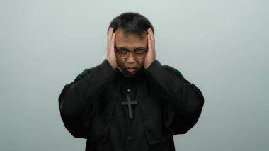 Papaz kıyafeti giymiş Asyalı bir adam arka planda sıkıntı içinde, duygularını ve dini temasını aktarıyor..