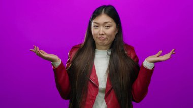 Kırmızı ceketli, uzun saçlı, parlak pembe arka planda jestleri olan bir kadın oyuncu karışıklığı ve yönü gösteriyor..