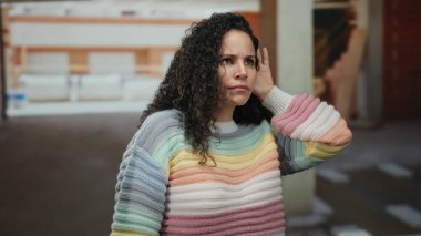 İnşaat alanında renkli bir kazak giyen İspanyol kadın kısmen inşa edilmiş bir evde dikkatlice dinlerken merakını dile getiriyor..