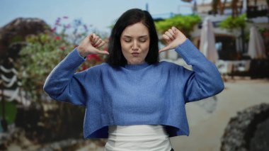 Terasta kendine güvenen bir kadın, canlı çiçeklerle dolu bir sokak restoranının arka planına ve açık havada oturmaya karşı memnuniyet gösteriyor..