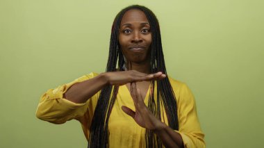 Sarı saçlı bir kadın, izole edilmiş sarı duvar arkabahı ile işaret ediyor. Mola kavramı. Yetişkin Afro-Amerikan kadın..