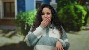 Gözlüklü kadın, gün ışığında çizgili süveter giyip arka planda ağaçlar olan sokakta şaşırdı. Meraklı ve etkileyici İspanyol kadın tepkileri sergiliyor..