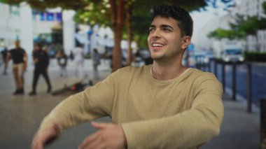 Erkek adam kollarını kaldırır ve onları caddenin karşısına dağıtır. Genç İspanyol adam dışarıda durup neşeyle gülümserken..