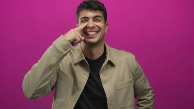 Genç İspanyol gülümseyen portre parmak pozu veren adam arka plana bakarken burnunu tutuyor..