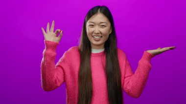 Pembe kazaklı çekici bir kadın gülümsüyor ve işaret veriyor..