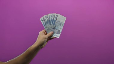 El ele tutuşan Güney Koreli, çarpıcı bir mor arka plana karşı banknotlar kazandı, mali temalar ve para yönetimi erkek perspektifi vurgulandı.