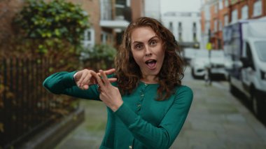 Şehirli şehir sokaklarında hashtag sembolü taşıyan bir kadın, yeşil kazak giyiyor, enerjik bir şekilde gülümsüyor, sosyal medyayı ve yaşam tarzını ön plana çıkarıyor..