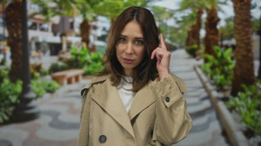 Etrafı gür ağaçlarla çevrili canlı bir park ortamını ve canlı bir açık hava atmosferini gösteren bir kadın..