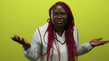 Gözlüklü ve örgülü bir kadın açık sarı arka planda duruyor şüphe ve güven gibi çeşitli ifadeler sergiliyor..