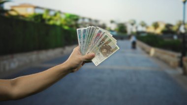 Bir şehir caddesinde elinde Polonya 'nın zloti banknotları olan bir adam, açık şehir ortamında canlı şehir arkaplanı ile döviz veya mali işlemleri sergiliyor..