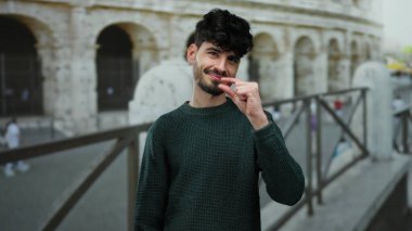 Roma 'da şehir merkezindeki Roma Kolezyumu' nda küçük boy el kol hareketi yapan genç bir adam. Çekici İspanyol erkeği yaratıcılığını ifade ediyor..