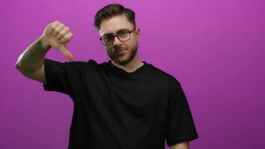 Sakallı beyaz bir genç, canlı pembe bir arka plana karşı olumlu bir jest yapıyor. İzole bir ortamda memnuniyetsizlik ya da hoşnutsuzluk gösteriyor..