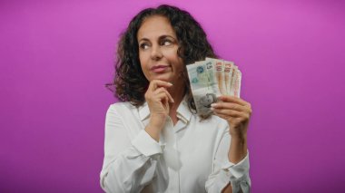 Soyutlanmış mor bir geçmişe karşı elinde İngiliz sterlinli banknotlar tutan orta yaşlı bir kadın, finansal değerlendirmeyi öneriyor..