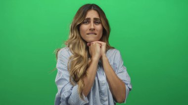 Bir fotoğraf stüdyosunda çizgili tişört giyen ve elleri çenesinin altında olan genç sarışın kadın; endişe gerginliği kaygısı.