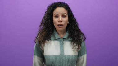 Mor bir arkaplan üzerinde duygularını ifade eden bir kadın, bir süveter giyiyor, yalıtılmış, gösterişli saç dokusu ve gençlik.