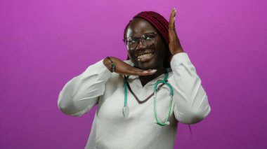 Gülümseyen Afro-Amerikan kadın doktor steteskopla canlı pembe bir arka plana karşı şakacı poz veriyor, kendine güven ve neşe saçıyor..