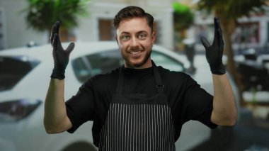 Sakallı garson, eldivenli elleriyle büyük bir jest yapıyor. Şehir caddesinde önlük giyiyor. Arka planda da da güvenle gülümseyen bir araba var..