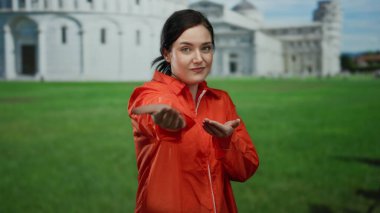 Turuncu hapishane tulumu giymiş bir kadın İtalya 'daki Pisa Kulesi' nin önünde el kamerasına uzanıyor. Hapishaneyi ikonik mimariyle harmanlayan eşsiz bir sahneyi yakalıyor..