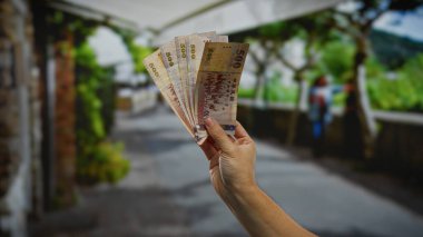 Şehir dışında bulanık bir zeminde el ele tutuşan Tayvan doları, canlı bir şehir ortamındaki yatırımları ve iş kavramlarını gösteren bulanık bir arka plan..