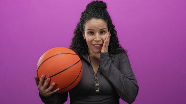 Elinde basketbol topu tutan kadın, parlak pembe arka planda yalnız başına koyu renk ceket giyiyor enerjik duyguları, gençlik ruhunu ve spor hevesini yakalıyor.