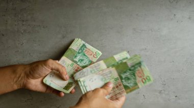 Elleri beton zeminde Hong Kong doları sayan bir adam.