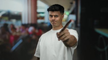 Kenar mahallede kendine güveni olan, açık havada beyaz gömlek giyen genç bir adam.