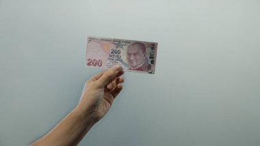 Beyaz arka planda Türk lira banknotunu tutan adam, izole edilmiş bir ortamda finansal konseptleri gösteriyor..