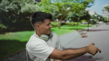 Parktaki genç adam, kulaklık takıp hayali bir halatı çekerek doğadaki dinamik bir anı yakalıyor..