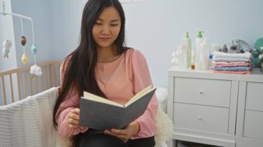 Bebek odasında beşikte kitap okuyan kadın, bebek malzemeleri ile çevrili, rahat bir apartman atmosferinde, barışçıl iç rahatlamayı temsil ediyor..