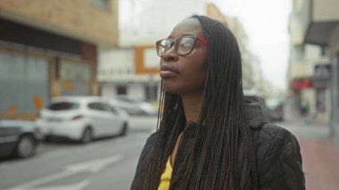 Örgü ören kadın şehir sokaklarında gözlük takıyor. Meşgul şehir hayatının ortasında afro amerikan güzelliği ve modası sergiliyor..