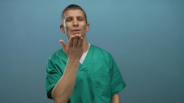 Yeşil üniformalı bir adam mavi arka planda öpüşüyor. Nazik bir ifadeyle izole edilmiş..