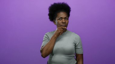 Derinden düşünen bir kadın, parlak bir mor arka plana karşı duruyor. Rahat bir tişört giyiyor. Münferit bir ortamda tefekkür ve içgözlem yansıtıyor..