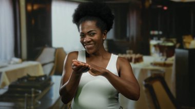 Lokantada gülümseyen bir kadın para harcayan, neşe ve güven saçan bir jest yapıyor..