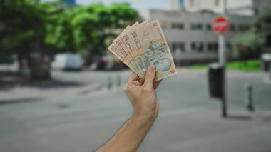 Elinde Romen lei banknotları olan bir adam, bir şehir sokaklarında el parası sergiliyor..