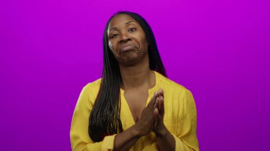 Sarı bluzlu kadın canlı pembe arka planda duruyor. Uzun örgüleri ve sakin ifadesiyle izole stüdyo ortamında kendine güveni tam bir güzellik ve tarz sergiliyor.