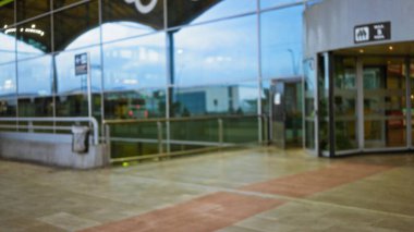 Modern bir uluslararası ulaşım merkezi ayarında odak dışı detaylar içeren cam pencereleri ve girişi olan bir havaalanı terminalinin bulanık görüntüsü.