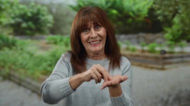 Parktaki son sınıf öğrencisi İspanyol kadın, açık hava ortamında duygu gösterisi yapan yemyeşil bir ortam ile çevrili..